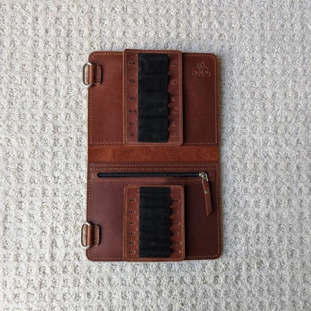 A whiskey brown leather needle case open to show black elastic needle holders 