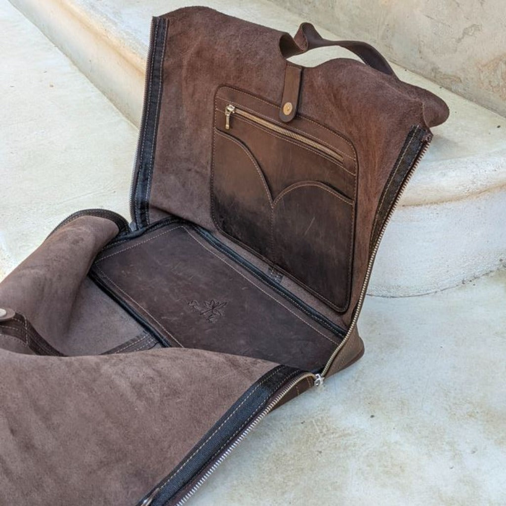 The Boundless leather bag in the color Chocolate unzipped to lay flat to show the inside pockets