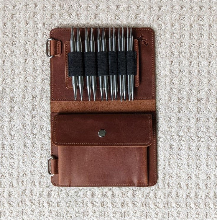Whiskey colored leather knitting needle case open with needles shown in black elastic slots 