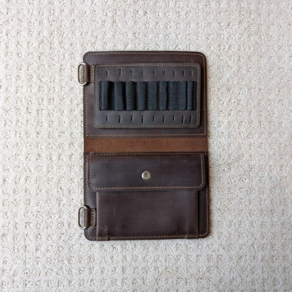 Dark brown leather knitting case open to show black elastic tabs to hold needles 