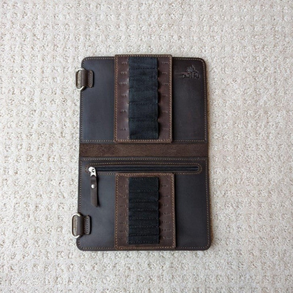 A chocolate leather needle case open to review black elastic slots for holding needles