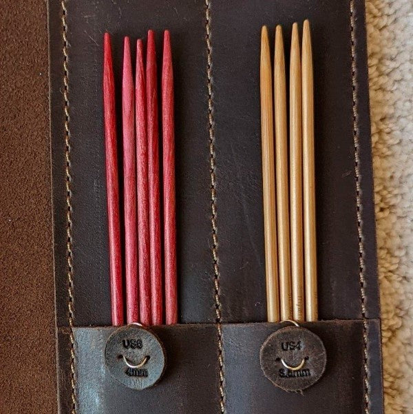 A chocolate brown leather case with DPNs showing two small, round needle size markers clipped to it.