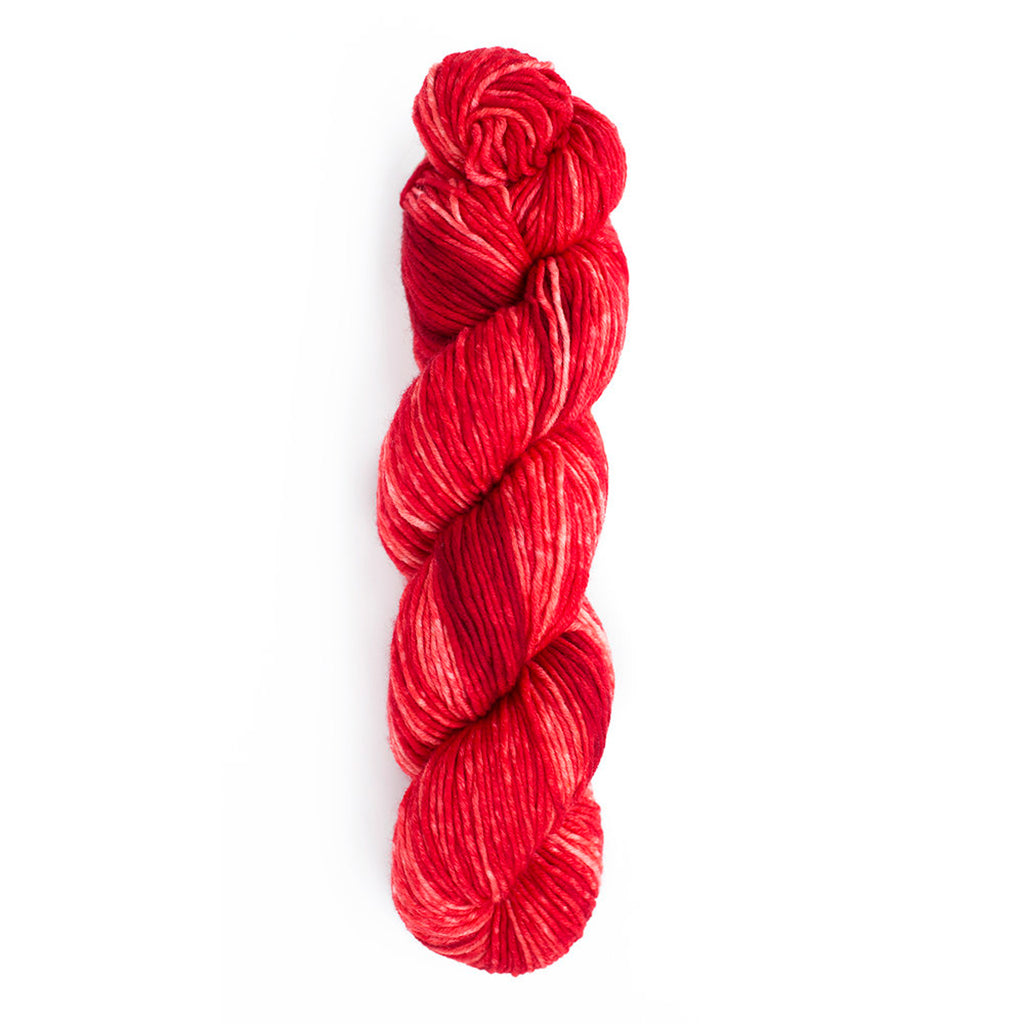 A skein of Monokrom Worsted, color 4051 which is a bright cherry red.