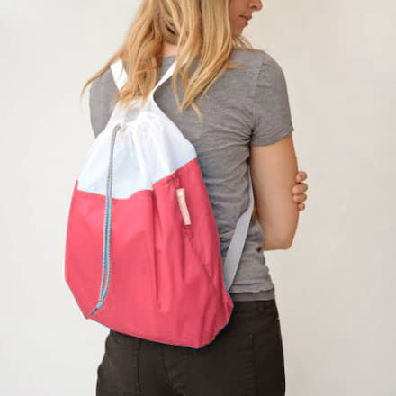 A person wearing Flip and Tumble backpack in coral color.