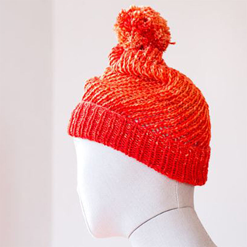 A bright Urth Yarns Monokrom Worsted Flux Hat with a pom pom on a mannequin.