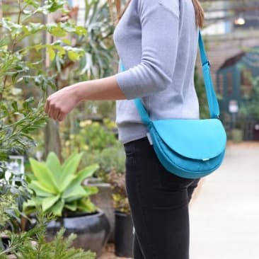 Person standing outside wearing an aqua colored little purse.