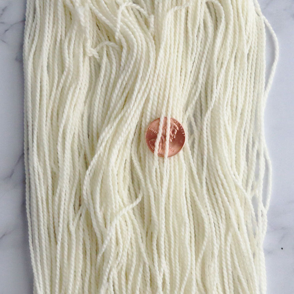 Close up of one mini skein of undyed high twist sock yarn