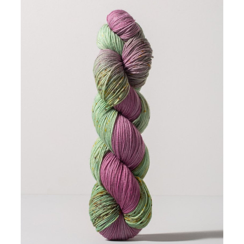 Gusto Wool Carmen Fingering 1409 - a light purple-pink colorway with speckled mint green, and yellow