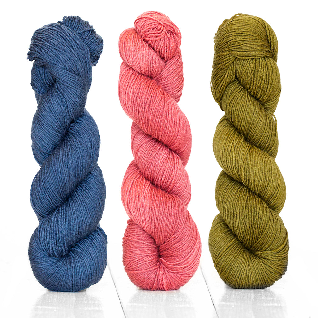 Three skeins of Harvest Fingering in the colors Indigo, Cranberry, and Fig.